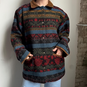 May include: A patterned jacket with a brown corduroy collar and trim. The jacket features a button-up front, two pockets, and a colorful design with red, blue, green, and brown elements. The jacket is a medium length.