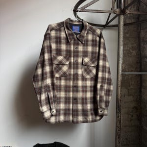 May include: A set of three ceramic mugs with a speckled, matte finish. The mugs are in shades of cream, light brown, and dark brown. Each mug has a simple, minimalist design, perfect for coffee or tea.