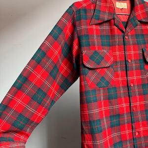 K&ouml;nnte beinhalten: Ein rot, gr&uuml;n und braun kariertes Button-Down-Hemd mit langen &Auml;rmeln. Das Hemd hat zwei Brusttaschen und einen Kragen. Der Stoff scheint ein mittelschweres Material zu sein, das f&uuml;r k&uuml;hleres Wetter geeignet ist.
