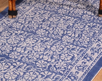 May include: A rectangular area rug featuring a deep blue background with a repeating white floral pattern. The design includes a central field of dense flower motifs surrounded by a distinct decorative border with a similar floral pattern.