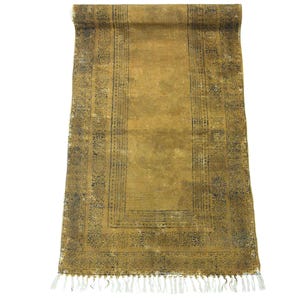 Puede incluir: Una alfombra de pasillo rectangular con un color base amarillo mostaza y un patrón de borde gris carbón desgastado. La alfombra presenta un campo central con una textura sutil y un fleco decorativo a lo largo del borde inferior.