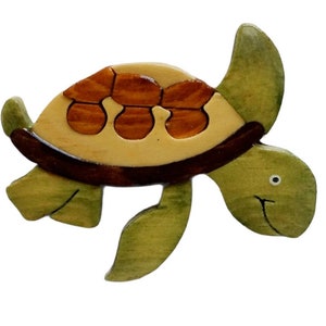 May include: A wooden turtle figurine with a green body and a brown shell. The shell is made of multiple pieces of wood, creating a unique pattern.