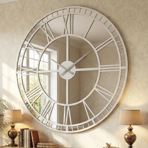 May include: A large, circular wall clock with a white frame and Roman numerals. The clock is mounted on a beige wall above a wooden console table. The room also features a sofa, lamps, and a potted plant.