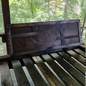 May include: A dark brown wooden sign with a carved Texas-shaped design. The sign is hanging on a wooden porch swing.