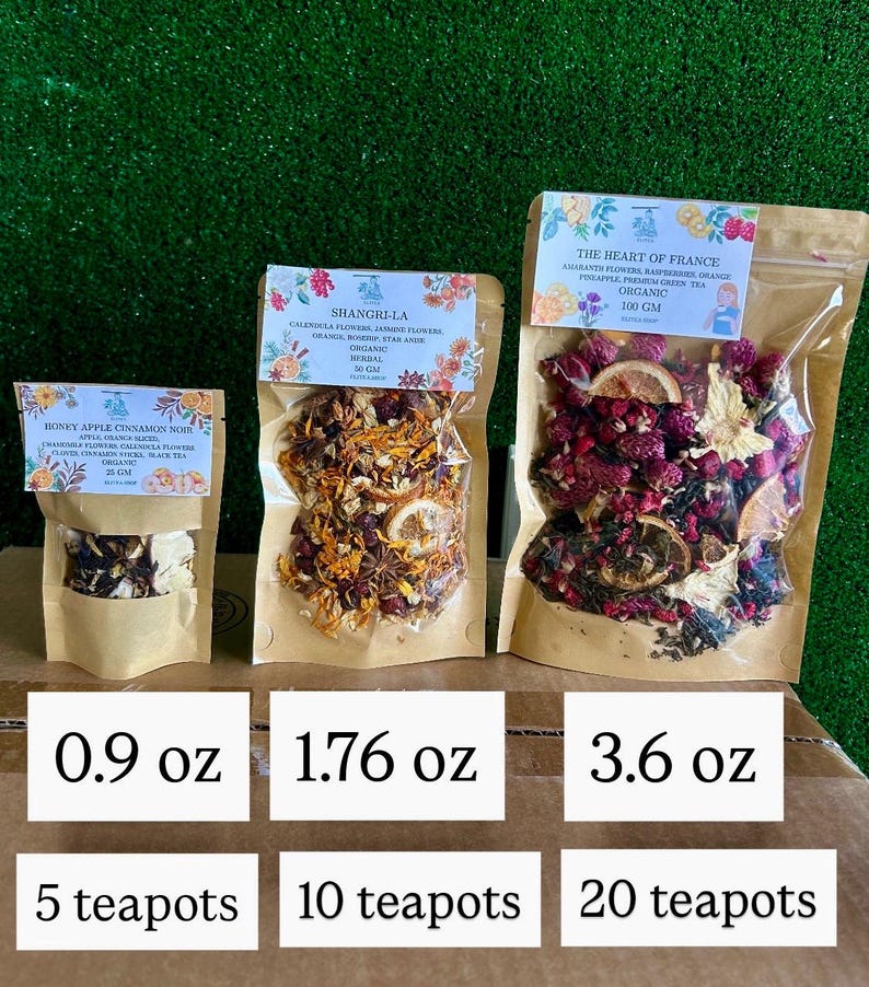 May include: Three sealed bags of organic herbal tea blends. The bags are labeled with the names "Honey Apple Cinnamon Noir", "Shangri-La", and "The Heart of France". Each bag contains a different blend of dried flowers, fruits, and herbs. The bags are labeled with the weight in ounces and the number of teapots.