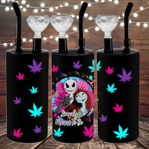 May include: Three black water pipes with a Jack Skellington and Sally design. The pipes have a clear glass bowl and a black silicone hose. The design features a pink, blue, and white background with black outlines. The text "Simply Meant to Be" is printed on the pipe.