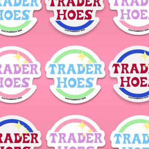May include: A collection of colorful stickers with the text "TRADER HOES" in various color combinations. Each sticker has a circular design with a starburst and the text "ELECTRAMERICA 2025". The stickers are on a pink background.