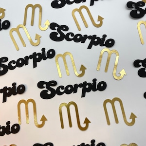 May include: Black and gold paper cutouts of the zodiac sign Scorpio. The sign is depicted as a stylized letter "M" with an arrow pointing upwards. The word "Scorpio" is written in a retro font.