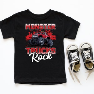 Może przedstawiać: Czarny t-shirt z grafiką czerwonego monster trucka i tekstem "Monster Trucks Rock".