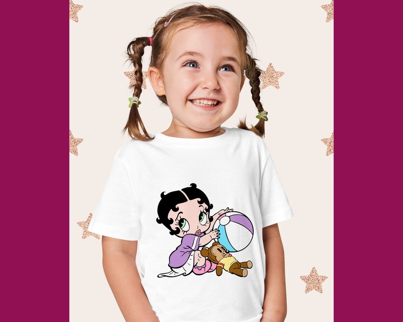 May include: A white t-shirt featuring a cartoon image of a girl with black hair and a purple dress playing with a beach ball and a teddy bear.