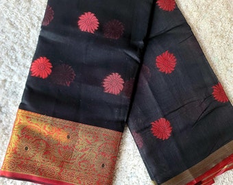 May include: Black saree with a red and gold border. The saree has a repeating pattern of red flowers on a black background.