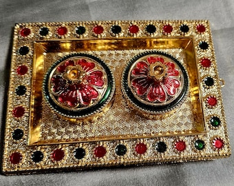 May include: A gold-colored decorative tray with two round containers. The containers have red and green floral designs. The tray and containers are adorned with red, green, and black gemstones.