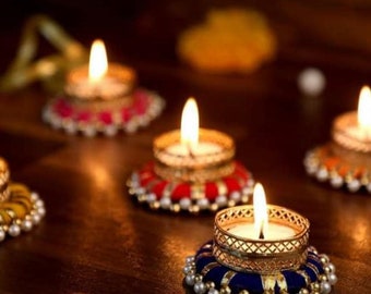 Puede incluir: Cinco portavelas decorativos con velas de té encendidas. Los portavelas están hechos de metal y tela con una variedad de colores y patrones, incluyendo rojo, azul, amarillo y dorado.