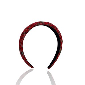 Pu&ograve; includere: Fascia per capelli rossa con un motivo dorato e nero.
