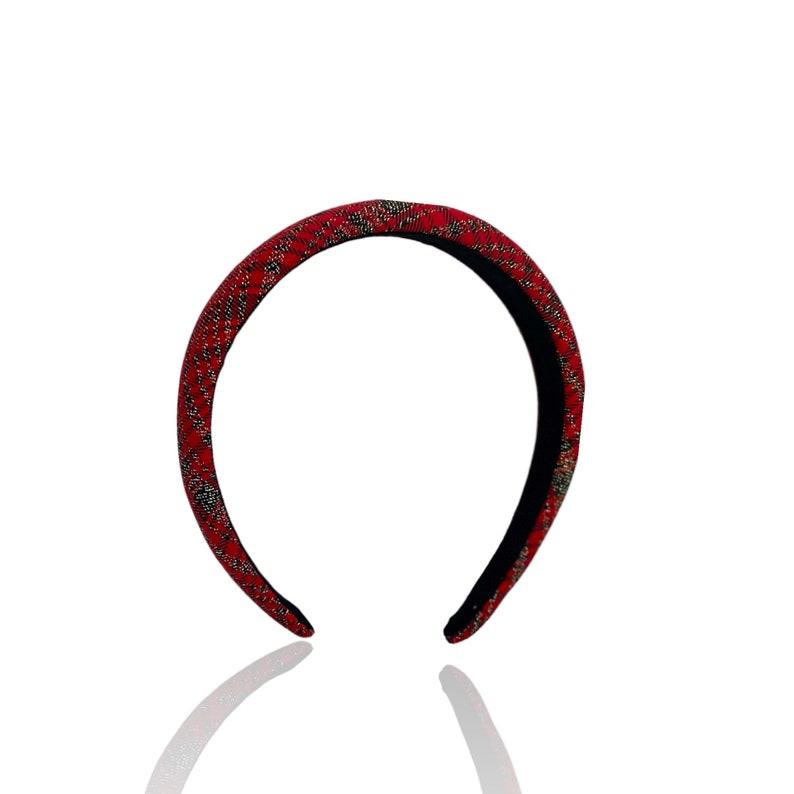 Pu&ograve; includere: Fascia per capelli rossa con un motivo dorato e nero.