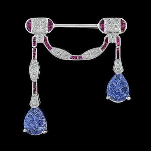 May include: A silver brooch featuring a teardrop-shaped blue stone and a row of red stones. The brooch has a delicate design with a white metal frame.