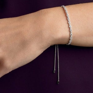 May include: A silver bracelet with a delicate chain and a row of sparkling clear crystals. The bracelet has a sliding closure, allowing for a custom fit.
