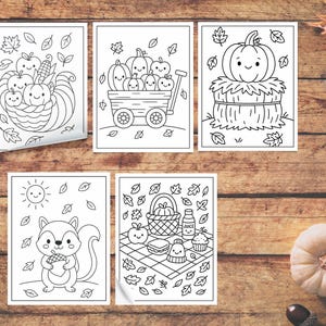 May include: Five black and white coloring pages featuring fall-themed illustrations. The images include pumpkins, a cornucopia, a squirrel with an acorn, and a picnic scene with a smiling cupcake. The pages are on a wooden surface.