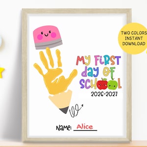 May include: A framed print featuring a yellow handprint shaped like a pencil with a pink eraser top. The text reads "MY FIRST DAY OF SCHOOL 2026-2027" with red and green apple illustrations. Below, the word "Name:" is followed by the name "Alice".
