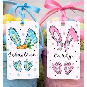 May include: Two Easter-themed gift tags with bunny ears, names, and footprints. One tag has blue ears, a carrot, and the name "Sebastian." The other has pink ears, a bow, and the name "Carly." Both tags are decorated with dots and Easter eggs.