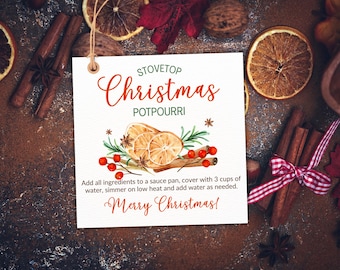 Op de afbeelding: Een wit label met de woorden "Stovetop Christmas Potpourri" in rode letters. Het label bevat een aquarel illustratie van gedroogde sinaasappelschijfjes, kaneelstokjes en bessen. De tekst "Merry Christmas!" is ook opgenomen.