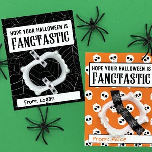 May include: Two Halloween-themed cards with the text "HOPE YOUR HALLOWEEN IS FANTASTIC". One card is black with a spiderweb design, the other is orange with skull graphics. Both cards have a plastic set of fangs and black spiders.