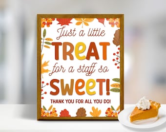 May include: A framed sign with the text "Just a little TREAT for a staff so SWEET! THANK YOU FOR ALL YOU DO!" in orange, brown, and yellow. The sign is decorated with autumn leaves and berries. A slice of pumpkin pie with whipped cream on a white plate.