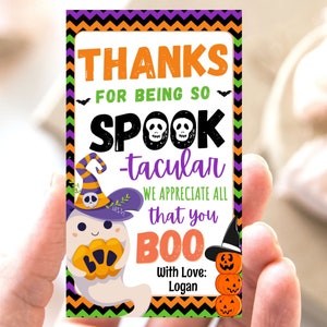 May include: A Halloween-themed gift tag with the words "THANKS FOR BEING SO SPOOK-tacular" in orange, black, and purple. A cartoon ghost and pumpkins are featured. The tag is signed "With Love: Logan."