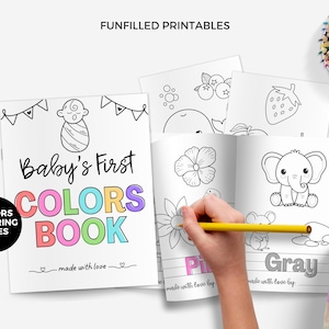 Puede incluir: Un libro para colorear para niños titulado "Baby's First Colors Book" con texto e ilustraciones coloridas. El libro está abierto en páginas con dibujos lineales de una flor, un elefante y otras imágenes. Una mano está coloreando con un lápiz amarillo. Lápices de colores en un recipiente.