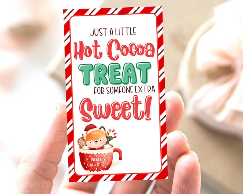 以下が含まれることがあります： 赤と白のストライプのカードに「Just a little Hot Cocoa Treat for someone extra Sweet!」の文字と、赤いマグカップに入った漫画のキツネが描かれており、マグカップには「Merry Christmas」の文字が書かれています。