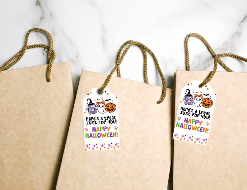 May include: Three brown paper gift bags with rope handles. Each bag has a white tag with Halloween-themed illustrations and text that reads "Here's a treat just for you! Happy Halloween!" The tags feature a ghost, pumpkin, and the word "Boo".