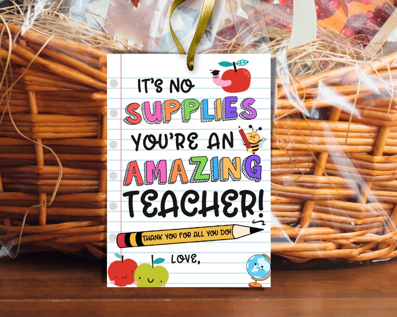 May include: A gift tag with the message "It's No Supplies You're An Amazing Teacher!" in colorful text. The tag has a lined paper design with illustrations of an apple, pencil, bee, and globe. A gold ribbon is attached.