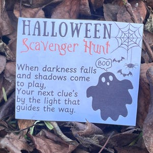 May include: A Halloween Scavenger Hunt sign with a ghost illustration, spiderweb, and bats. The sign reads "When darkness falls and shadows come to play, Your next clue's by the light that guides the way."