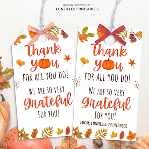May include: Two white gift tags with a fall theme. Each tag has a pumpkin illustration and the words "Thank you for all you do! We are so very grateful for you!" The tags are decorated with fall leaves and tied with a ribbon.