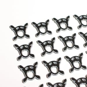 May include: Twenty-four black and white plastic game pieces with a skull and crossbones design. Each piece has a small hole in the center.