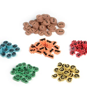 Może przedstawiać: Zbiór kolorowych elementów gry o różnych kształtach i kolorach. Są brązowe okrągłe elementy z numerami, niebieskie elementy w kształcie liści, pomarańczowe poszarpane elementy, czerwone elementy z odciskami łap, zielone elementy z wirami i żółte elementy z wirami.