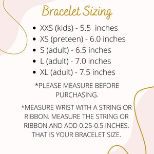 Op de afbeelding: Een roze en gouden afbeelding met instructies over hoe je je pols kunt meten voor de maatvoering van armbanden. De afbeelding bevat de tekst "Bracelet Sizing" en geeft verschillende maten met bijbehorende metingen in inches. De tekst bevat ook instructies over hoe je je pols kunt meten met een touwtje of lint.