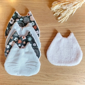 May include: Four stackable, soft, green and white patterned fabric baby bibs with a cat face design. One white terry cloth bib with a cat face design.