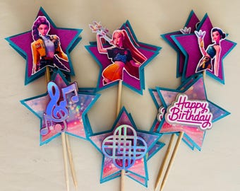 May include: A collection of star-shaped cake toppers with images of animated characters and musical notes. The toppers are in shades of pink, teal, and purple, with wooden sticks for insertion into a cake. One topper says "Happy Birthday".
