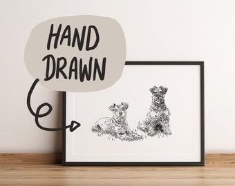 May include: Black and white hand-drawn art print featuring two dogs. One dog is lying down, and the other is sitting upright. The print is in a black frame and has the words "HAND DRAWN" above the image.