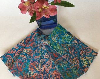 May include: Set of six teal blue and coral patterned fabric napkins. The napkins have a floral design and are folded in a fan shape.