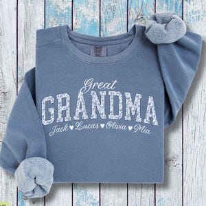 Pu&ograve; includere: Felpa blu jeans con le parole "Great Grandma" in lettere bianche con un motivo floreale. I nomi Jack, Lucas, Olivia e Mia sono stampati sotto. Un elastico per capelli abbinato &egrave; sulla spalla.