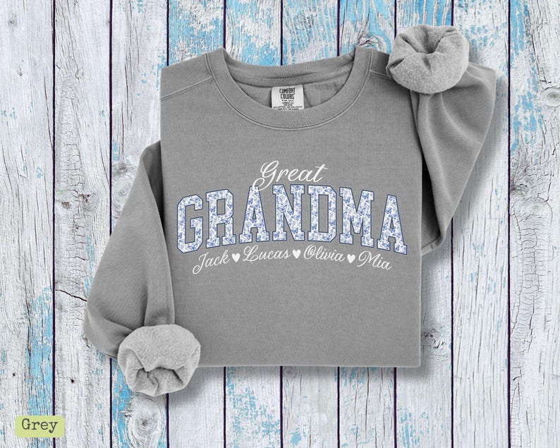Pu&ograve; includere: Una felpa grigia con la scritta "Great Grandma" in bianco e lettere floreali. I nomi Jack, Lucas, Olivia e Mia sono stampati sotto. La felpa ha un girocollo e maniche lunghe.