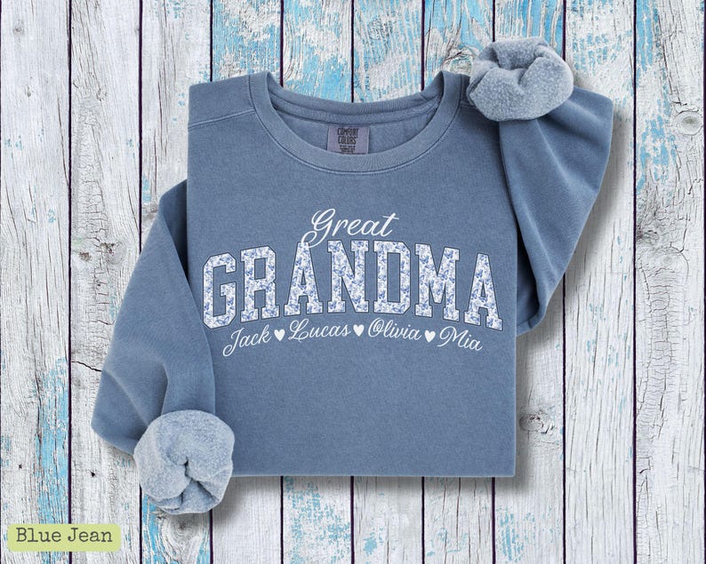 Pu&ograve; includere: Felpa blu jeans con le parole "Great Grandma" in lettere bianche con un motivo floreale. I nomi Jack, Lucas, Olivia e Mia sono stampati sotto. Un elastico per capelli abbinato &egrave; sulla spalla.