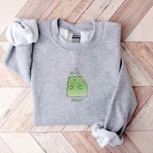 May include: Gray sweatshirt with a green frog graphic and the word "Ribbet" printed below. The frog is surrounded by small stars.