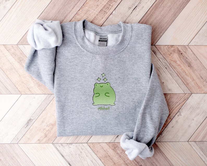 May include: Gray sweatshirt with a green frog graphic and the word "Ribbet" printed below. The frog is surrounded by small stars.