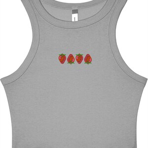 May include: A gray crop top with a scoop neck and embroidered strawberries. The strawberries are red with green leaves and are arranged in a horizontal line across the chest.