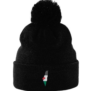 May include: Black knit beanie with a large pom-pom on top. The beanie features an embroidered design of a map of Palestine in the colors of the Palestinian flag: black, white, green, and red. The beanie is a winter accessory.