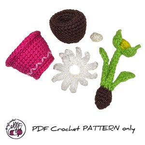 May include: Crochet pattern for a flower pot, flower, and soil. The pot is pink, the flower is white with a yellow center, and the soil is brown. The pattern is available as a PDF download.