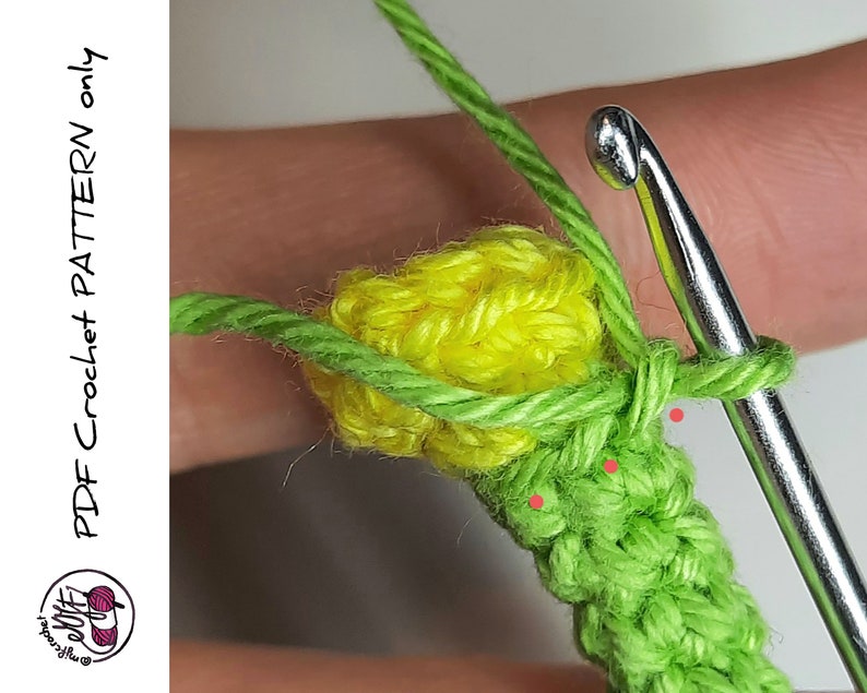 May include: A close-up of a crochet project with a yellow flower and green leaves. The crochet hook is visible in the image.